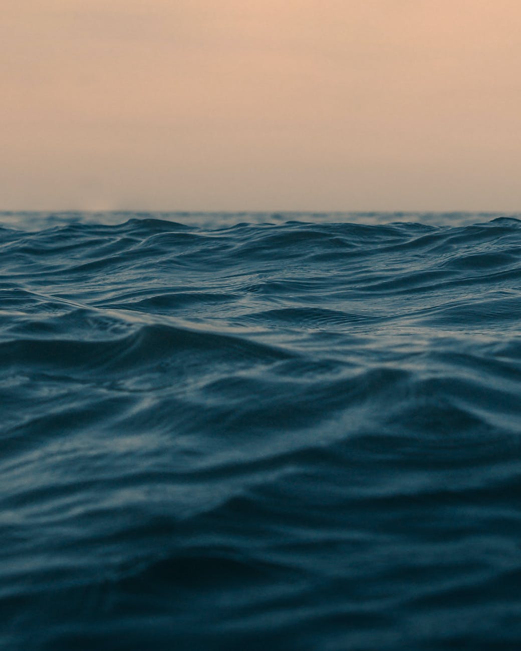 wavy ocean with horizon under sky at sunset